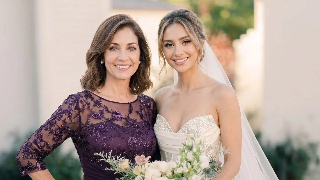 Mother of the bride in a plum lace gown posing with the bride at an outdoor wedding